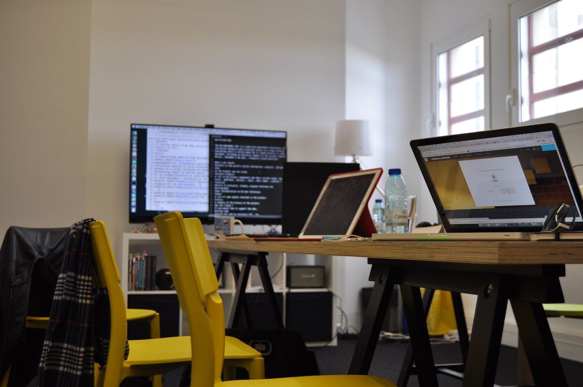 Laptops and a monitor on a trestle desk in the studio.