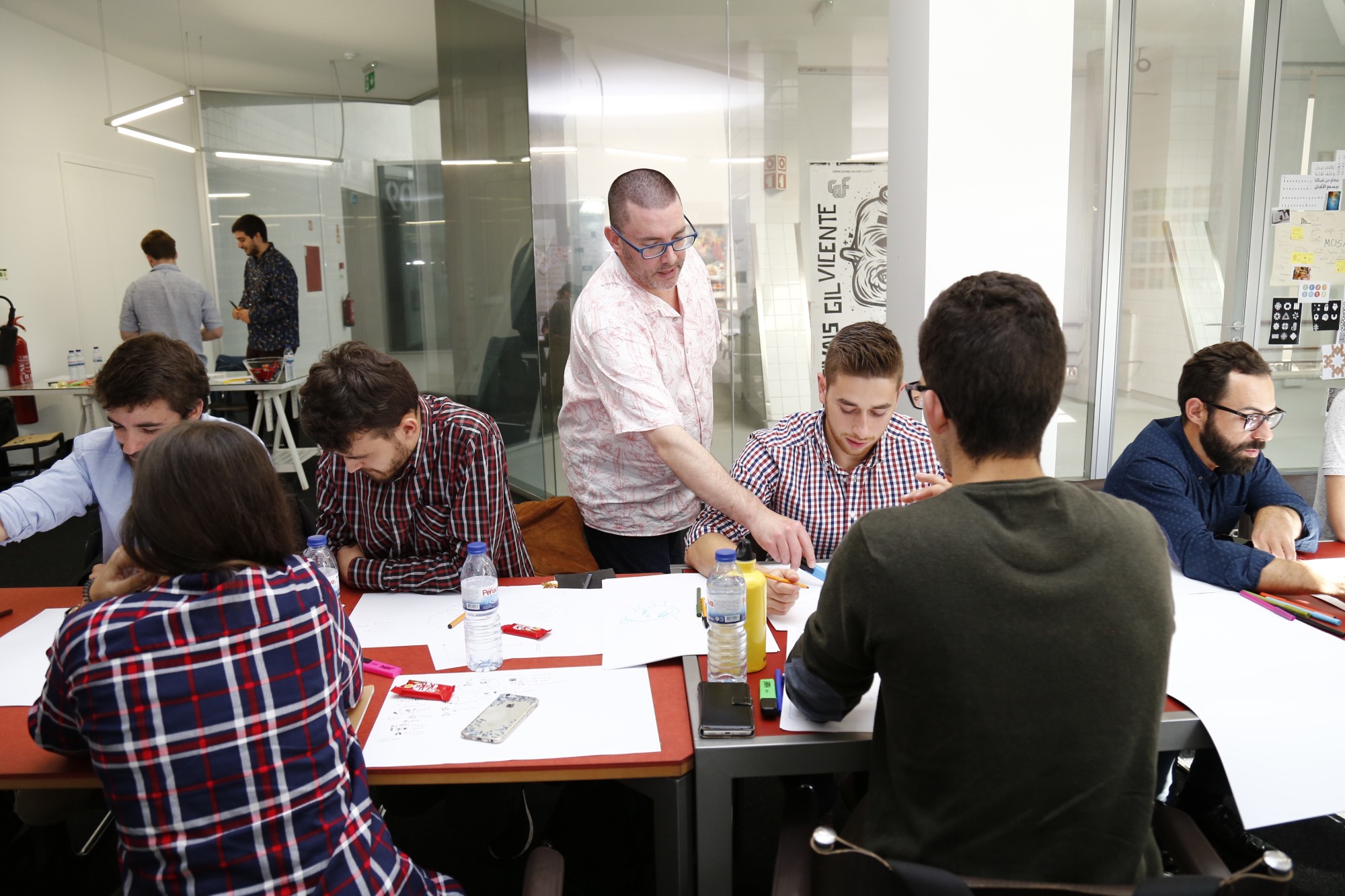 Chris Murphy helps students sketching at a shared table during the soft launch workshop