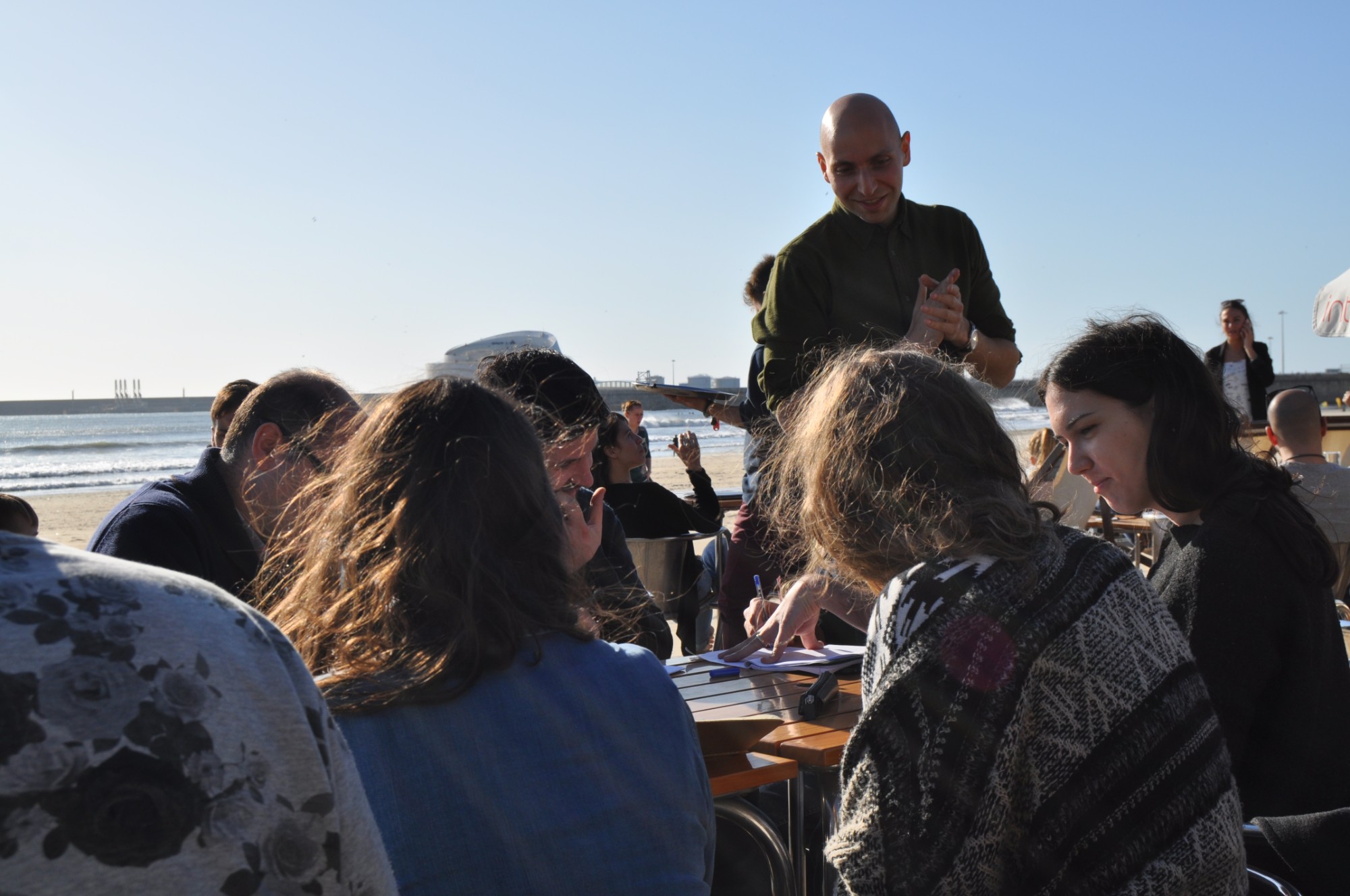 Vitaly Friedman talks with students around a table at a beach café by the sea