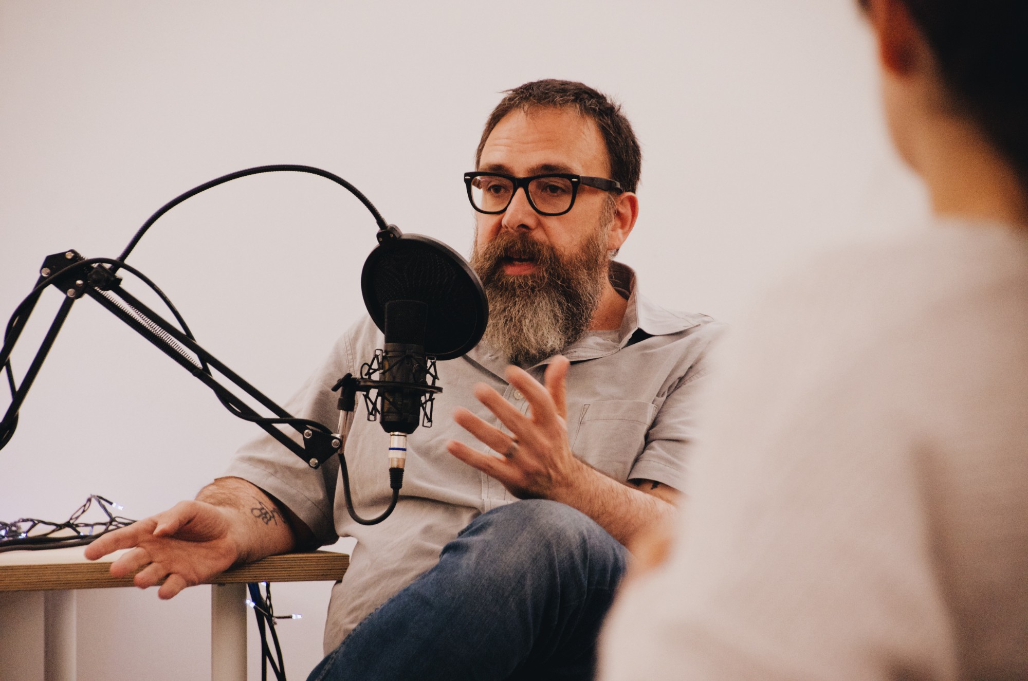 A guest talks into a studio microphone while recording a podcast episode at TNDS